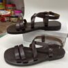 Sandalias de cuero marrón con tiras ajustables, ideales para el verano, mostradas sobre una superficie blanca.