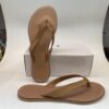 Chanclas de mujer de color marrón con tiras delgadas, sobre una superficie blanca y con una caja de fondo. Ideal para uso casual y veraniego.