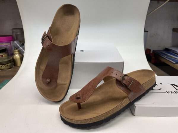 Sandalias de cuero marrón con suela de corcho, ideales para uso diario y comodidad. Diseño clásico con tira entre los dedos y hebilla ajustable.