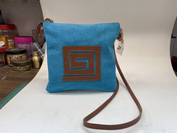Bolso cruzado de tela azul con diseño marrón en forma de espiral, ideal para uso diario y accesorios de moda.