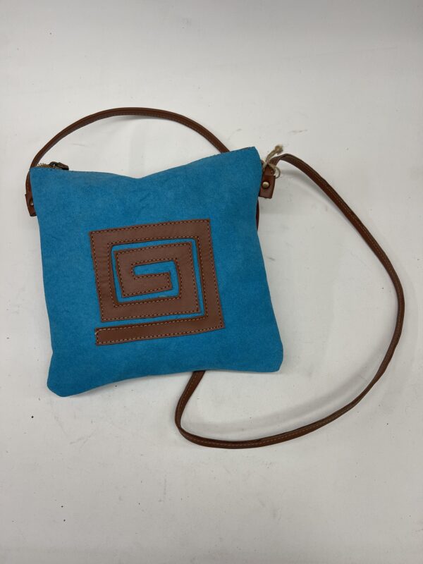 Bolso cruzado azul con diseño de espiral marrón y correa de cuero. Ideal para un look casual y moderno.